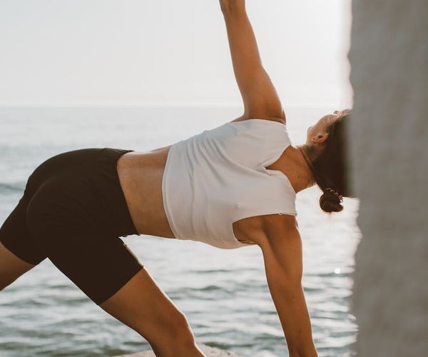 Person doing a gentle stretching yoga pose outdoors at sunrise.